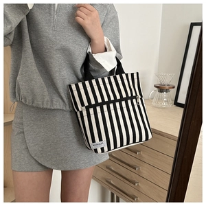 Detail of striped canvas tote bag with FASHION INSTINCT label and zipper pocket