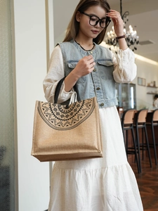 Linen tote bag with black geometric print held by a model in a cafe setting