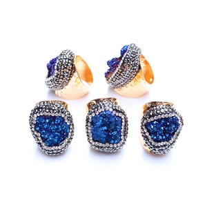 Close-up of five bohemian golden hammered rings featuring irregular blue druzy crystals