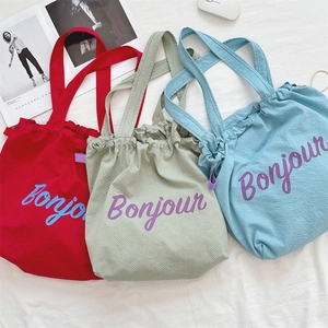 Detail of colorful drawstring tote bags in bubble gauze texture with Bonjour print