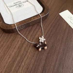 Détail du pendentif teckel mignon et breloque fleur sur collier chaîne argentée