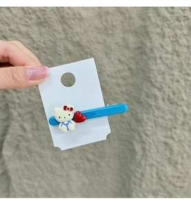 Nahaufnahme der blauen Acryl-Haarklammer mit Cartoon-Katze und rotem Herz auf Karte