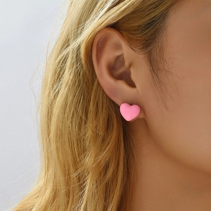 Close-up of a pink heart enamel earring on model ear for a Y2K subculture aesthetic