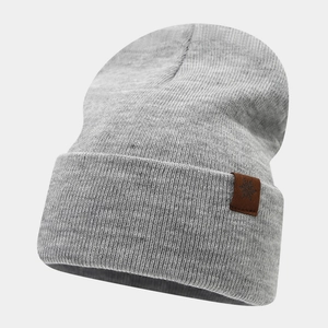Detail of grey knitted beanie with brown leather snowflake patch and thick ribbed texture