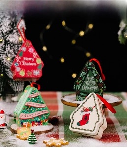 Detailed view of 4 festive Christmas tin gift boxes with hanging ropes and holiday prints