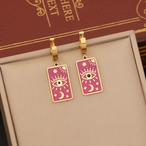 Detail of gold rectangular earrings with rose red enamel and celestial evil eye charms