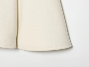 Detail of white wool coat hemline showing high-quality stitching and fabric texture