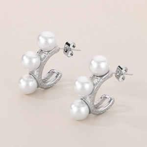 Detail view of silver C-shaped earrings with inlaid pearls and vintage textures