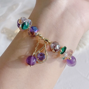 Close-up of gold bracelet with purple amethyst beads and sparkling zircon floral pendant