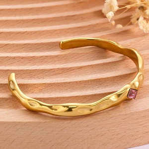 Detail of gold-plated hammered cuff bracelet featuring a square pink-purple zircon stone