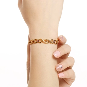 Close-up of pink round zircon stone set in a gold-plated link bracelet on female wrist