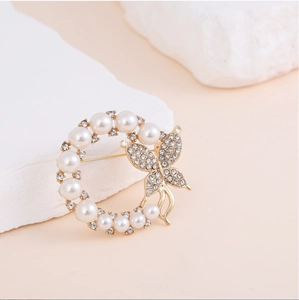 Macro view of gold flower brooch with pearls, rhinestones and butterfly detail