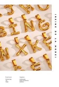 Macro detail of golden bamboo texture alphabet pendants B J N X K G on ivory surface