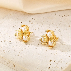 Macro shot of French vintage gold floral stud earrings with white pearls on a stone surface