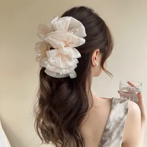 Dettaglio del grande fermaglio per capelli in organza crema con perle eleganti