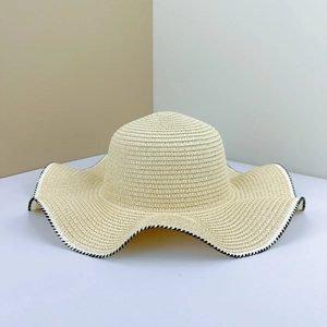 Detail of woven straw sun hat brim featuring black and white decorative stitching edge