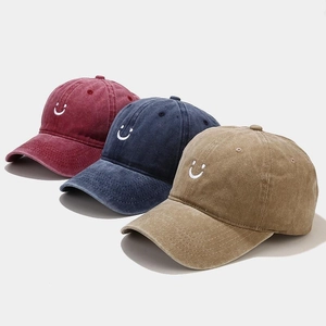Three washed cotton baseball caps with embroidered smiley faces in red, navy and khaki
