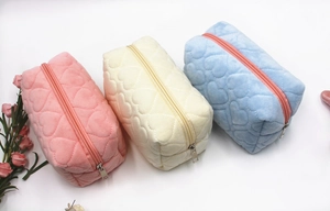 Detailed view of plush heart-quilted stationery pouches in pink, white, and blue