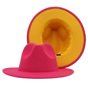 Detail of wide-brim bicolor fedora hat featuring magenta exterior and yellow interior