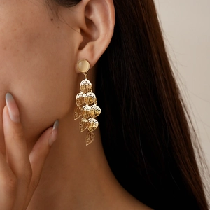 Close-up of golden leaf tassel earrings with cream cat eye stone on model side profile