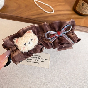 Détail d'une pince à cheveux à carreaux marron avec ours en peluche et nœud élégant