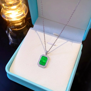 Macro shot of a geometric green square pendant necklace with white zircon in a blue gift box
