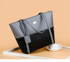 Detailed view of grey and black patchwork tote bag with smooth faux leather texture