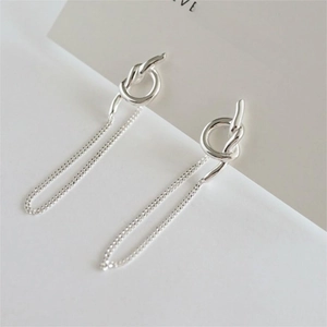 Macro shot of 925 sterling silver knot earrings with minimalist drop chains on display