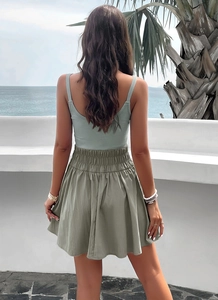 Rear view of an elegant sage green camisole and olive high-waist skirt on a beach terrace