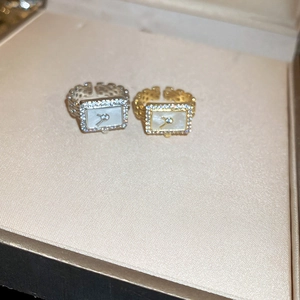 Detail of square watch-shaped rings in gold and silver with sparkling crystals
