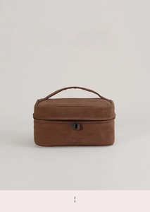 Macro detail of brown nubuck texture and dual zipper closure on a large cosmetic bag