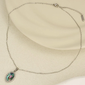 Macro view of oval abalone shell pendant with silver floral metal border on a fine chain
