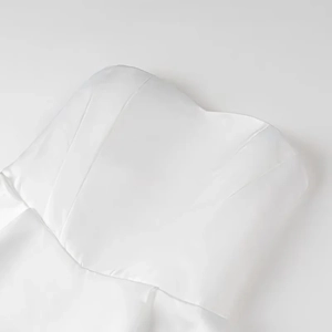 Detailed view of white satin strapless dress featuring vertical panels and silk-like texture