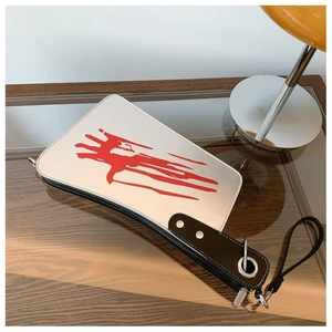 Detail of creative cleaver handbag showing bloody knife print and black handle strap