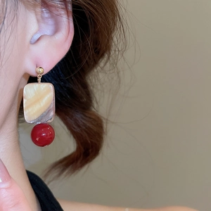 Detail of square shell and red bead drop earring worn by a model for a vintage aesthetic