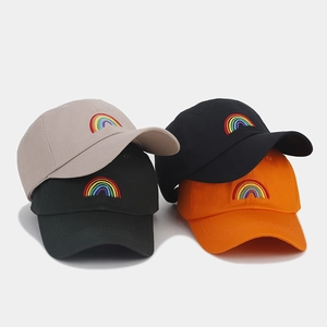 Stacked rainbow embroidery baseball caps in beige, black, and orange cotton twill fabric
