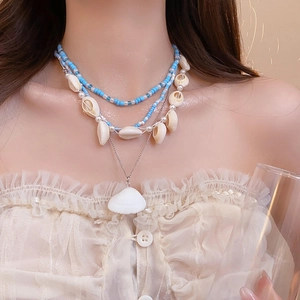 Detail of a 3-layer summer ocean necklace featuring sea shells, pearls, and blue beads
