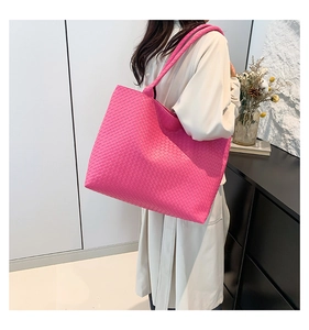 Detail view of large hot pink woven tote bag shown from side profile on shoulder