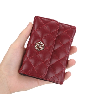 Red quilted leather card holder with hexagonal gold buckle and accordion folding