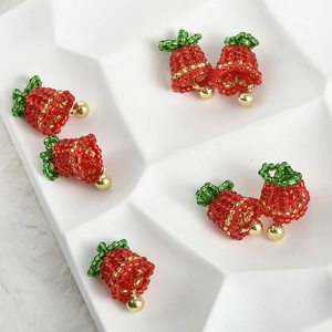 Detailed macro of handmade red and green beaded bell charms for DIY jewelry making