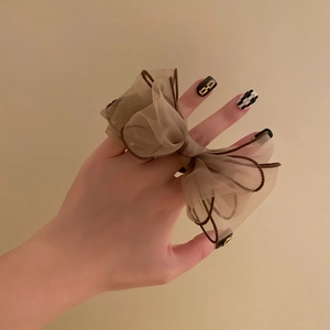 Detail of brown organza bow hair tie with dark brown edging shown on model wrist