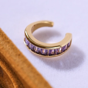 Macro shot of 18K gold-plated ear cuff featuring square-cut purple cubic zirconia crystals