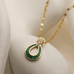 Macro detail of gold plated teardrop pendant with green stone and pavé zircon inlay