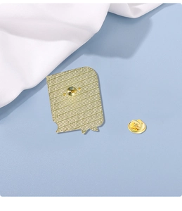 Detail view of the golden metal book brooch back with a secure round butterfly clutch