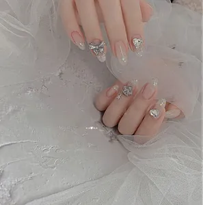 Détails de faux ongles de luxe avec nœuds argentés, diamants cœur et pendentifs