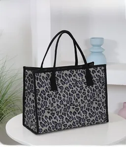 Detail view of a leopard print tote bag on a white table with a minimalist background