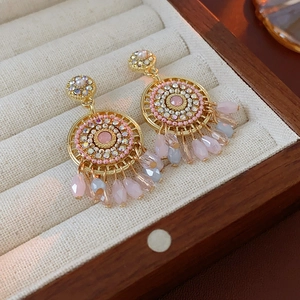 Detailed shot of vintage gold earrings with pink crystals and teardrop beads in a box