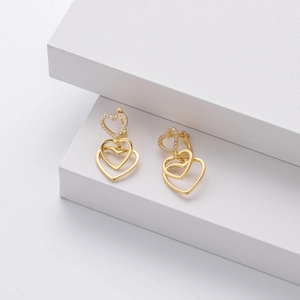 Detail of S925 silver golden double heart earrings with shimmering zircon pavé stones