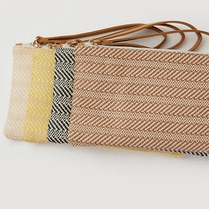 Detail showing woven straw clutches in cream, yellow, and brown with leather wristlets
