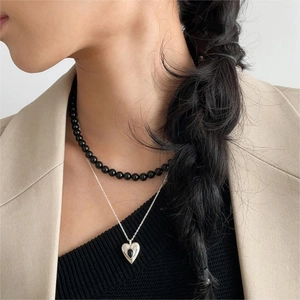 Double-layered 925 silver necklace with black beads and a heart pendant shown on a model